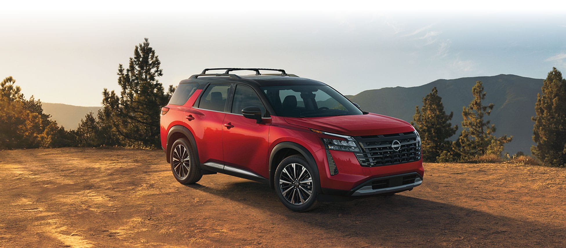 2026 Nissan Pathfinder front three-quarter view parked on a dirt overlook among pines