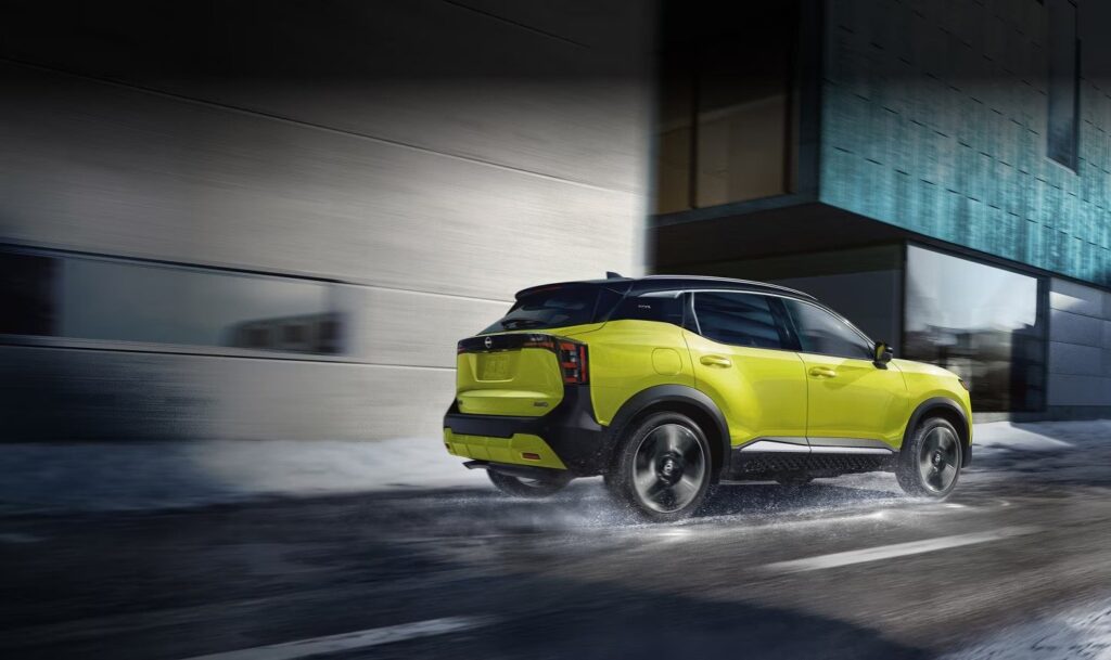 Yellow 2027 Nissan Kicks driving on a wet city road rear view driving on a wet city road